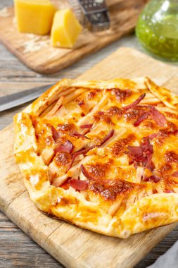 Açık gri mutfak arka planında hindi eti, parmesan peyniri ve mozzarella peynirli turta. Nefis ev yapımı, doyurucu hamur işleri.