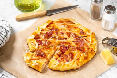 Açık gri mutfak arka planında hindi eti, parmesan peyniri ve mozzarella peynirli turta. Nefis ev yapımı, doyurucu hamur işleri.