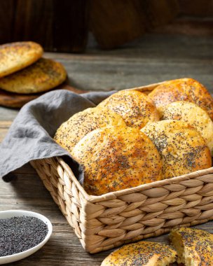 Açık gri ahşap mutfak masasında haşhaş tohumlu ev yapımı çörekler. Kahvaltı için lezzetli geleneksel İskandinav hamur işleri