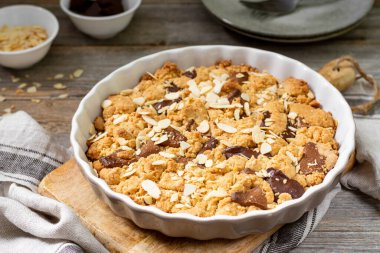 Gri ahşap mutfak arka planında, içinde süt ve acı çikolata bulunan ev yapımı kurabiye turtası. Lezzetli köylü tatlıları.