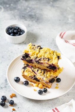 Açık gri ahşap mutfak masasında beyaz tabakta yaban mersinli kurabiyeler. Lezzetli ev yapımı tatlı hamur işleri