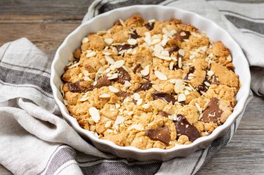 Gri ahşap mutfak arka planında, içinde süt ve acı çikolata bulunan ev yapımı kurabiye turtası. Lezzetli köylü tatlıları.