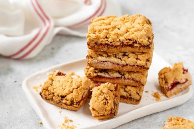 Açık gri mutfak masasında beyaz tabakta vişneli reçelli kurabiyeler. Lezzetli ev yapımı tatlı hamur işleri