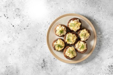 Krem peynirli mantar şampiyonları, tavuk filetosu ve parmesanlı açık gri mutfak masası manzaralı bir tabakta