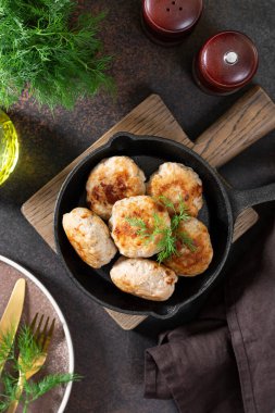 Kahverengi yemek masasının üstünde siyah tavada pirzola.