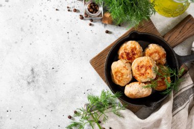 Hindi eti pirzolası, açık gri bir yemek masasının üstünde, siyah bir tavada.