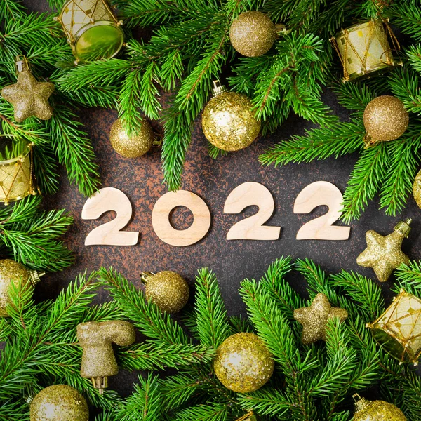 - Mutlu yıllar. Noel ağacının dallarında sarı ya da altın Noel süslemeleri. Ahşap numaraları 2022 olan şenlikli bir arka plan. Üst görünüm