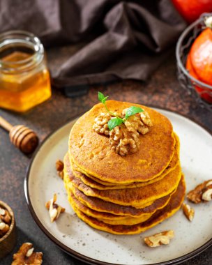 Koyu arkaplanda seramik tabakta balkabağı gözlemeleri.