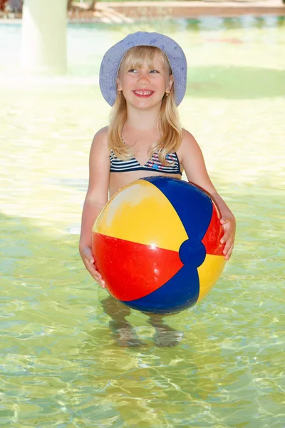 Nettes lächelndes kleines Mädchen hält Ball im Schwimmbad — Stockfoto