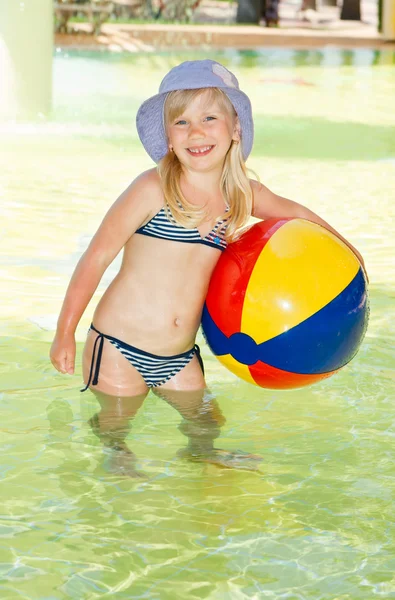 Nettes lächelndes kleines Mädchen hält Ball im Schwimmbad lizenzfreie Stockfotos