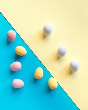 Yumurtaya, şekere, kapsüle, tatlıya benzeyen haplar, mavi ve sarı arka planda. Minimum konsept. Metin için kopyalama alanı olan kart.