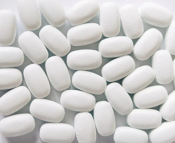 White pills on a white background. Oval white pills close up. Healthcare and medicine.