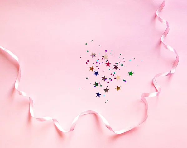 ピンクの背景に星や丸いピースの光沢のあるコンフェッティ フラットレイアウト トップビュー 薄いピンクのリボンで装飾 プロジェクトのフェスティバル背景 — ストック写真