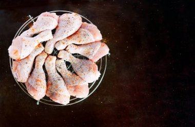 Saf tavuk bacağı ve metal bir ızgaranın üzerinde baharatlar. Koyu metal bir arka planda, yazı için yeri var. Yukarıdan görüntüle