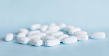 Açık mavi arka planda beyaz haplar. Sağlık ve İlaç Hizmetleri.