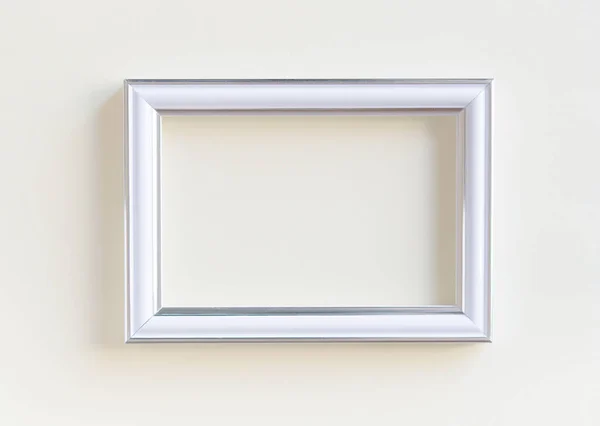 Blank white picture frame on a plain beige background. Empty poster mockup for art display.  No people.