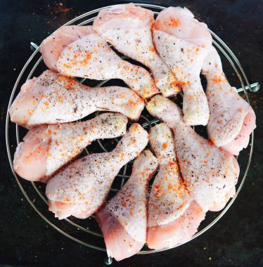 Saf tavuk bacağı ve metal bir ızgaranın üzerinde baharatlar. Koyu metal bir arka planda, yazı için yeri var. Yukarıdan görüntüle