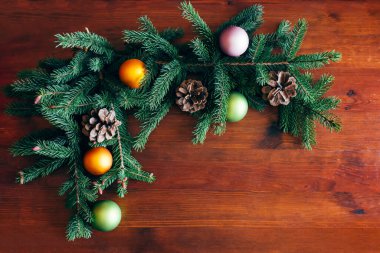 Noel arkaplanı, kahverengi ahşap arka planda yeşil kozalaklı çam dalları ve Noel topları. Sınır ve kopyalama alanı ile yaratıcı kompozisyon, üst görünüm. Yeni yıl, tatil, Noel, dekorasyon.