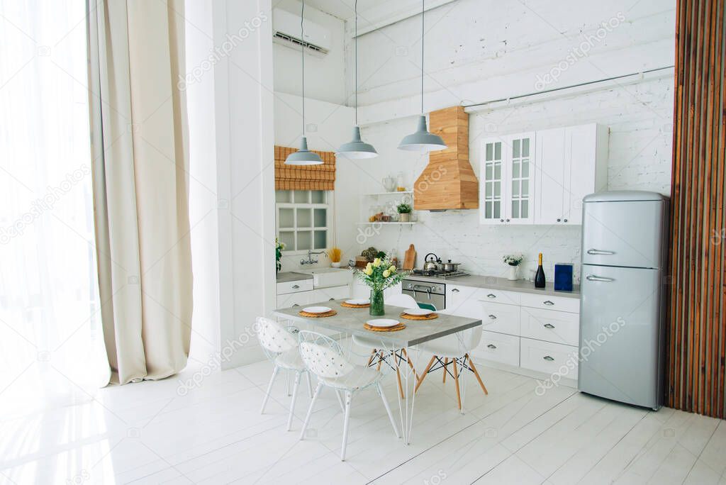 Minimal cozy light home style, scandinavian interior. White furniture with utensils, shelves with crockery and plants in pots, refrigerator in simple dining room, panorama, empty space