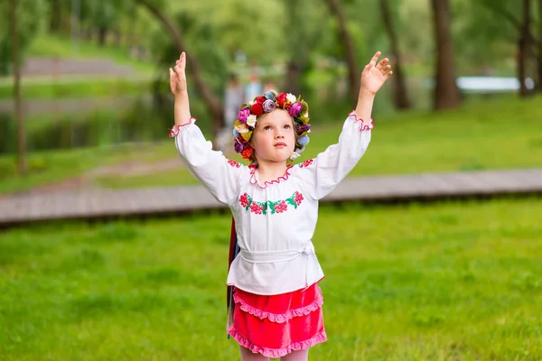 緑の背景にウクライナの民族衣装で楽しい若い女の子の肖像画 屋外だ 笑顔だ 抱擁のために手を伸ばし — ストック写真