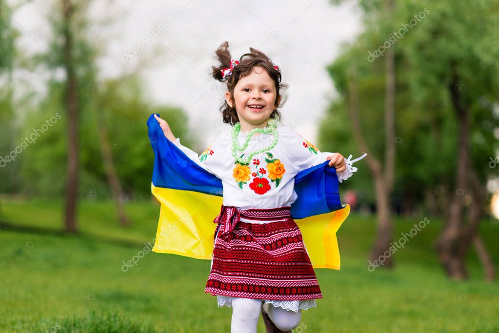 Happy girl with the flag of Ukraine. The girl is dressed in an embroidered shirt - the Ukrainian national dress. August 24 - Independence Day of Ukraine. postcard with patriotic symbols