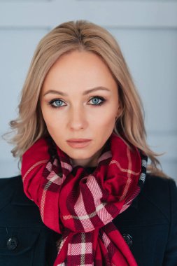 Mavi sonbahar ceketli ve kırmızı atkılı güzel sarışın kadın. Sonbahar ya da kış iç mekan portresi.