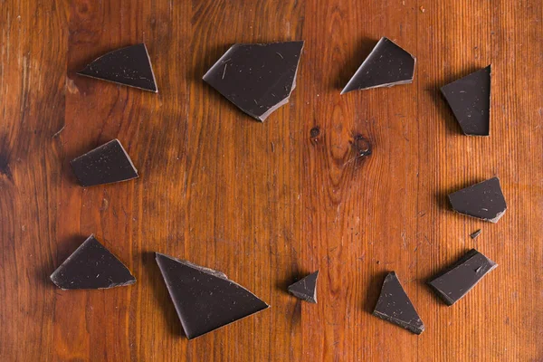 木製の茶色の背景にダークチョコレートの壊れた作品 — ストック写真
