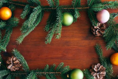Christmas background, green pine branches with cones and Christmas balls on a brown wooden background. Creative composition with border and copy space, top view. New year, holiday, christmas, 