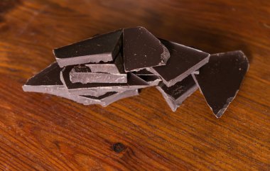Tahta kahverengi arka planda kırılmış siyah çikolata parçaları..