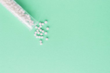 Homeopati ilacı alternatif bitkiler. Yeşil arka planda homeopatik globullar ve cam şişe. Sağlık ve Tıp Konsepti.