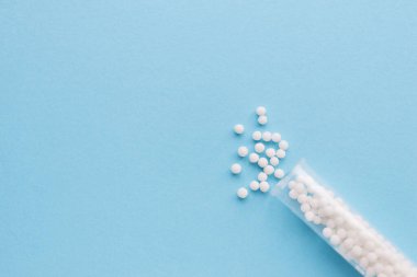 Homeopati ilacı alternatif bitkiler. Mavi arka planda homeopatik küreler ve cam şişe. Sağlık ve Tıp Konsepti.
