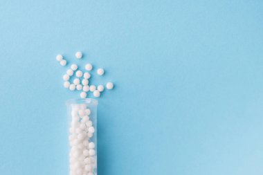 Homeopati ilacı alternatif bitkiler. Mavi arka planda homeopatik küreler ve cam şişe. Sağlık ve Tıp Konsepti.
