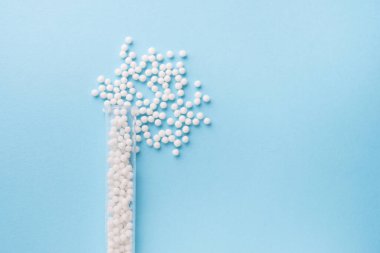 Homeopati ilacı alternatif bitkiler. Mavi arka planda homeopatik küreler ve cam şişe. Sağlık ve Tıp Konsepti.
