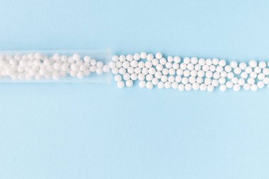 Homeopati ilacı alternatif bitkiler. Mavi arka planda homeopatik küreler ve cam şişe. Sağlık ve Tıp Konsepti.