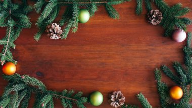 Noel arkaplanı, kahverengi ahşap arka planda yeşil kozalaklı çam dalları ve Noel topları. Sınır ve kopyalama alanı ile yaratıcı kompozisyon, üst görünüm. Yeni yıl, tatil, Noel, dekor