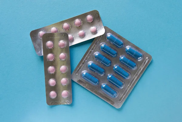 Blisters with pills, packaging with pills and capsules on a blue background