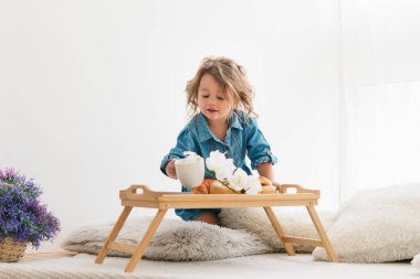 Kot mavisi elbiseli şirin küçük kız. İçinde kruvasan var. Kahvaltıda. Işık odası. Avrupa yarışı.