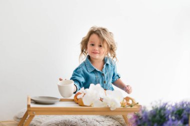 Kot mavisi elbiseli şirin küçük kız. İçinde kruvasan var. Kahvaltıda. Işık odası. Avrupa yarışı.