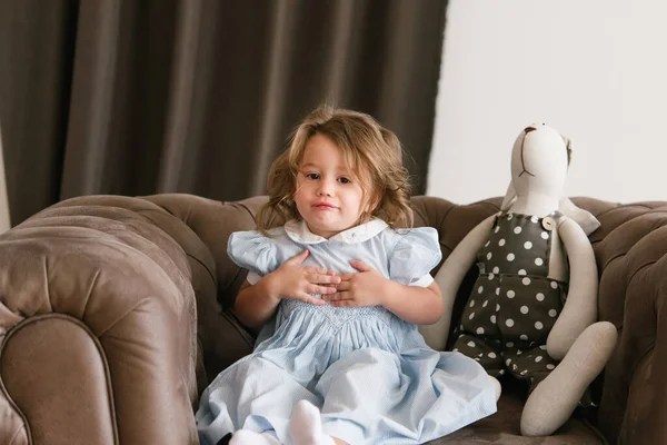 Mała Dziewczynka Szczęśliwym Uśmiechem Ubrana Niebieską Sukienkę Dziewczyna Siedzi Brązowym — Zdjęcie stockowe