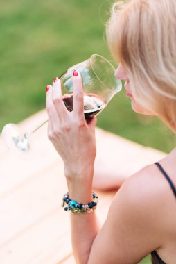 Elinde kırmızı şarap olan bir kadeh tutan kadın.