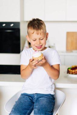 Çocuk doğum gününü pastayla kutluyor. Eller ve yüz krem içinde.