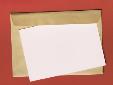 Kırmızı arkaplanda boş kağıt ve el işi zarfı