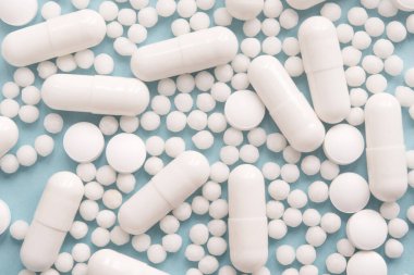 Dağılmış beyaz hap kapsülleri. Reklam, internet ya da diğer fikirler için özel tekliflere hazırlan. Tıbbi, eczane ve sağlık hizmetleri kavramı