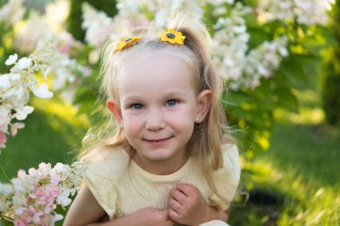 Tarlada çiçeklerin yanında komik at kuyruklu çok tatlı bir kız. Doğada gülümseyen çocuk. Bir yaz günü parkta yürümek.