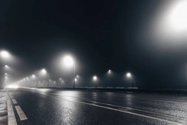 街路灯に照らされた霧深い夜の道 — ストック写真