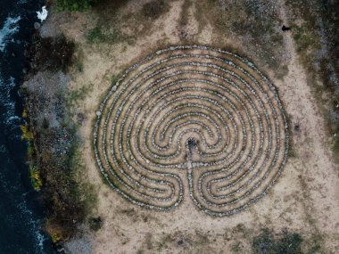 Spiral labyrinth made of stones on the cost, top view from drone. clipart