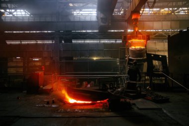 İşçi metalurji fabrikasında metal döküm işlemi yürütüyor.