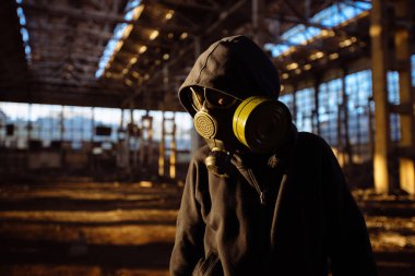 Terk edilmiş sanayi binasında gaz maskesi takan kişi