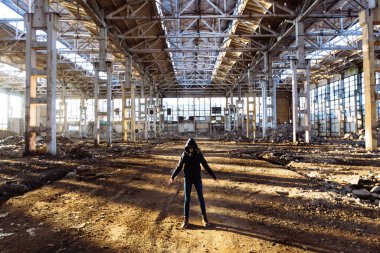 Terk edilmiş sanayi binasında gaz maskesi takan kişi