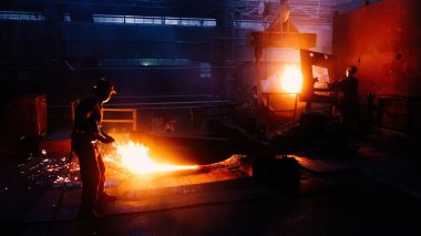İşçi metalurji fabrikasında metal döküm işlemi yürütüyor.